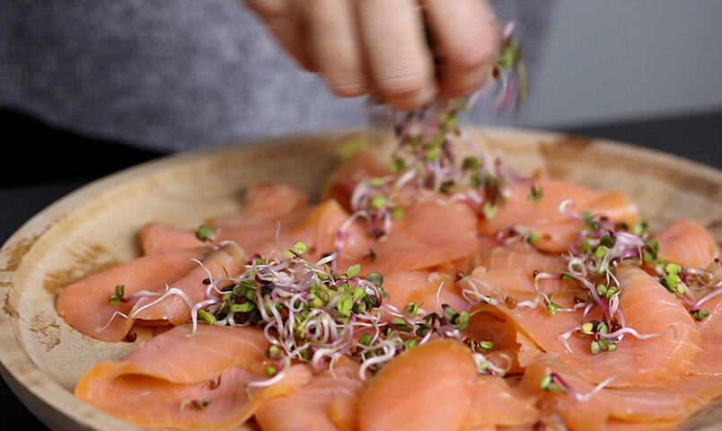 Ett fat med rökt lax som strösslas med rädisgroddar.